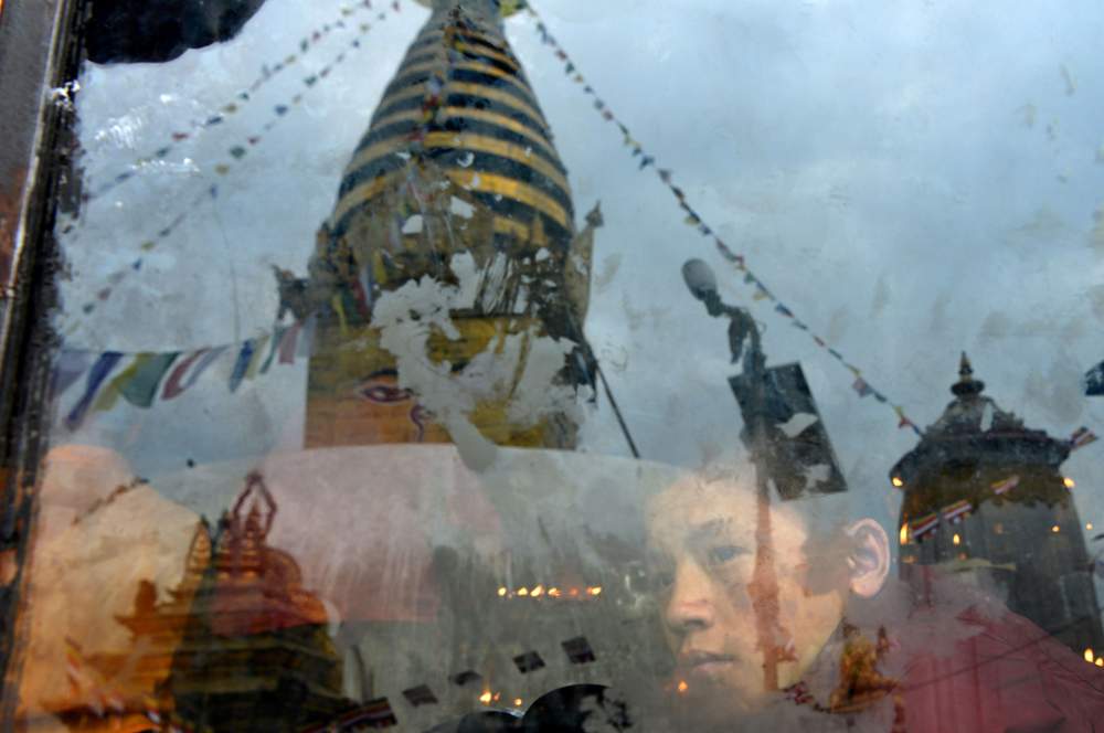 Un moine népalais regarde à travers une vitre les cérémonies célébrant la naissance de Bouddha, le 10 mai 2017 à Swayambunath.© Prakash Mathema \/ AFP